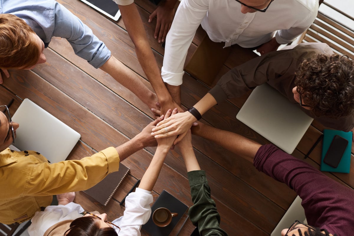 Diverese team of employees huddle with hands together